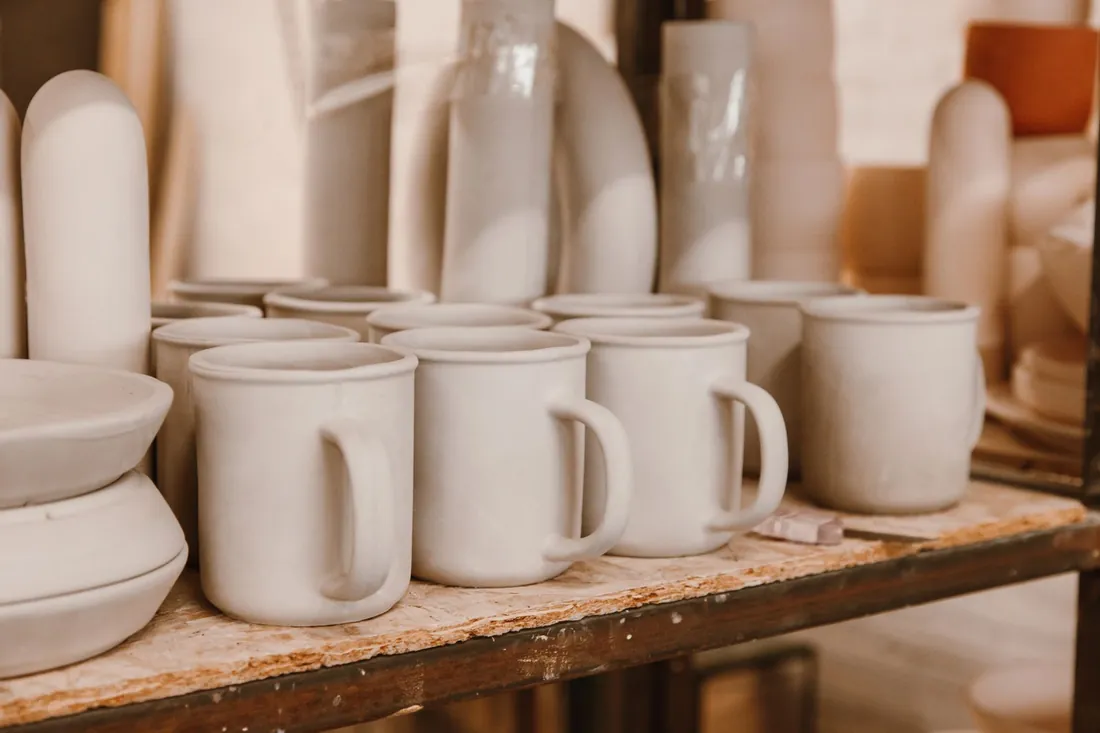 Piezas cerámicas coladas, sin esmaltar, secándose sobre una tabla en un taller